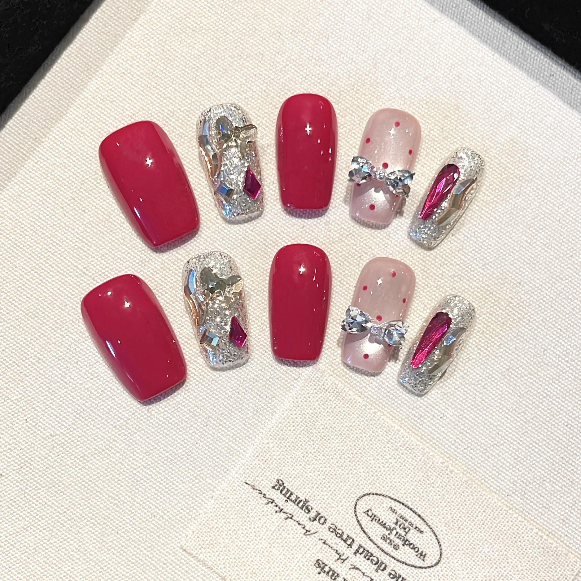 Nail Art Red - 10個入り、手作りの赤いネイルチップ。リボンとラインストーン、シルバーのラメが施され、繰り返し使えるので、女性の結婚式やパーティーに最適なネイルアートです。