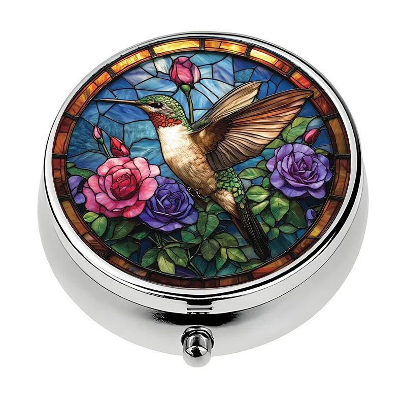 A small pill box, featuring a hummingbird and rose design, equipped with three compartments. It is a portable decorative vitamin storage box, suitable for carrying in a purse or bag.