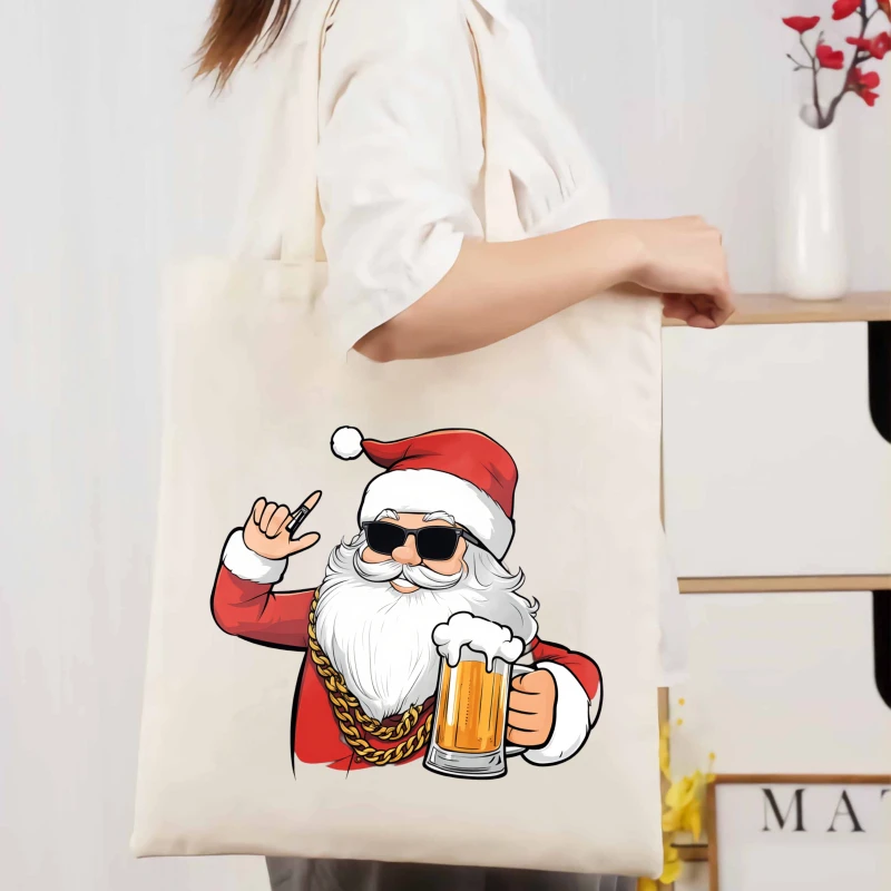 Un bolso tote de lona color crema con estampado de Papá Noel con gafas de sol y cerveza, adecuado para compras navideñas y uso diario.