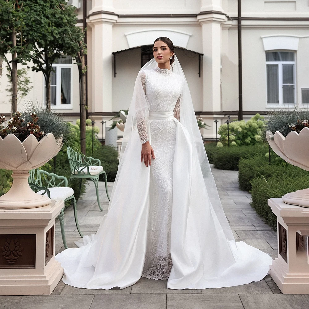 Suknia ślubna z białej koronki z dekoltem w kształcie litery O, z iluzorycznymi, długimi rękawami, trenem Watteau, długości do podłogi, o kroju syreny.