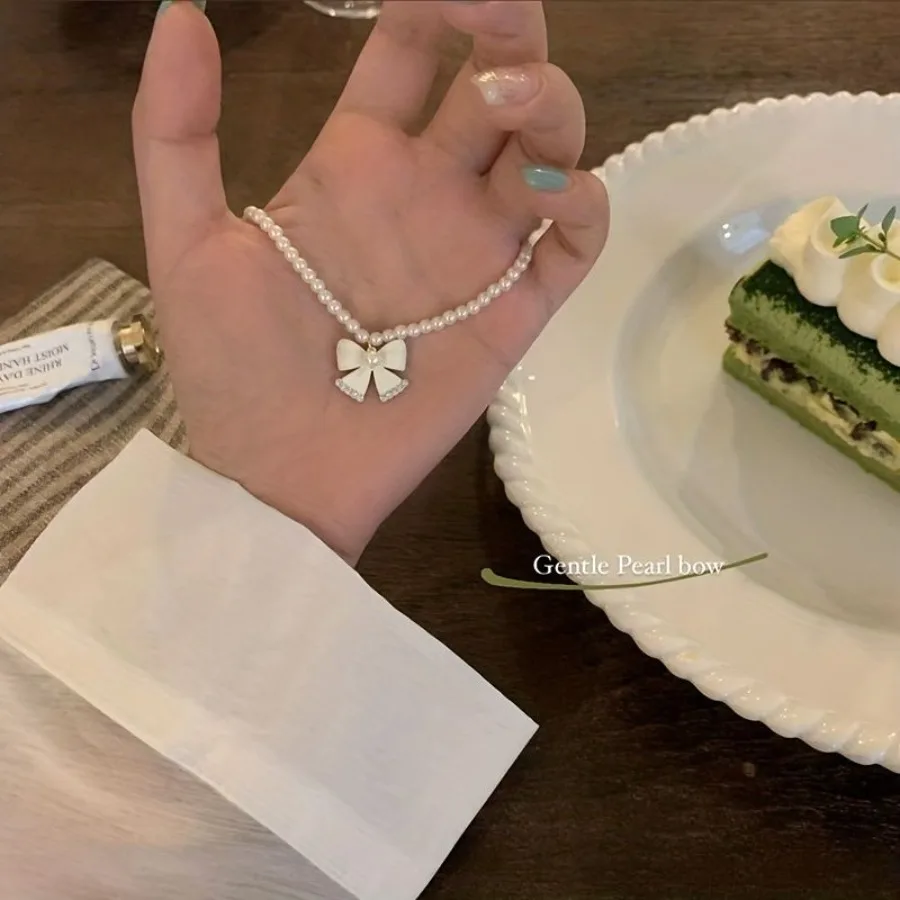 Naszyjnik damski w stylu kokieteryjnym z sztucznymi perłami, łańcuszkiem i zawieszką z kokardką, niszowy design, łańcuszek na obojczyk.