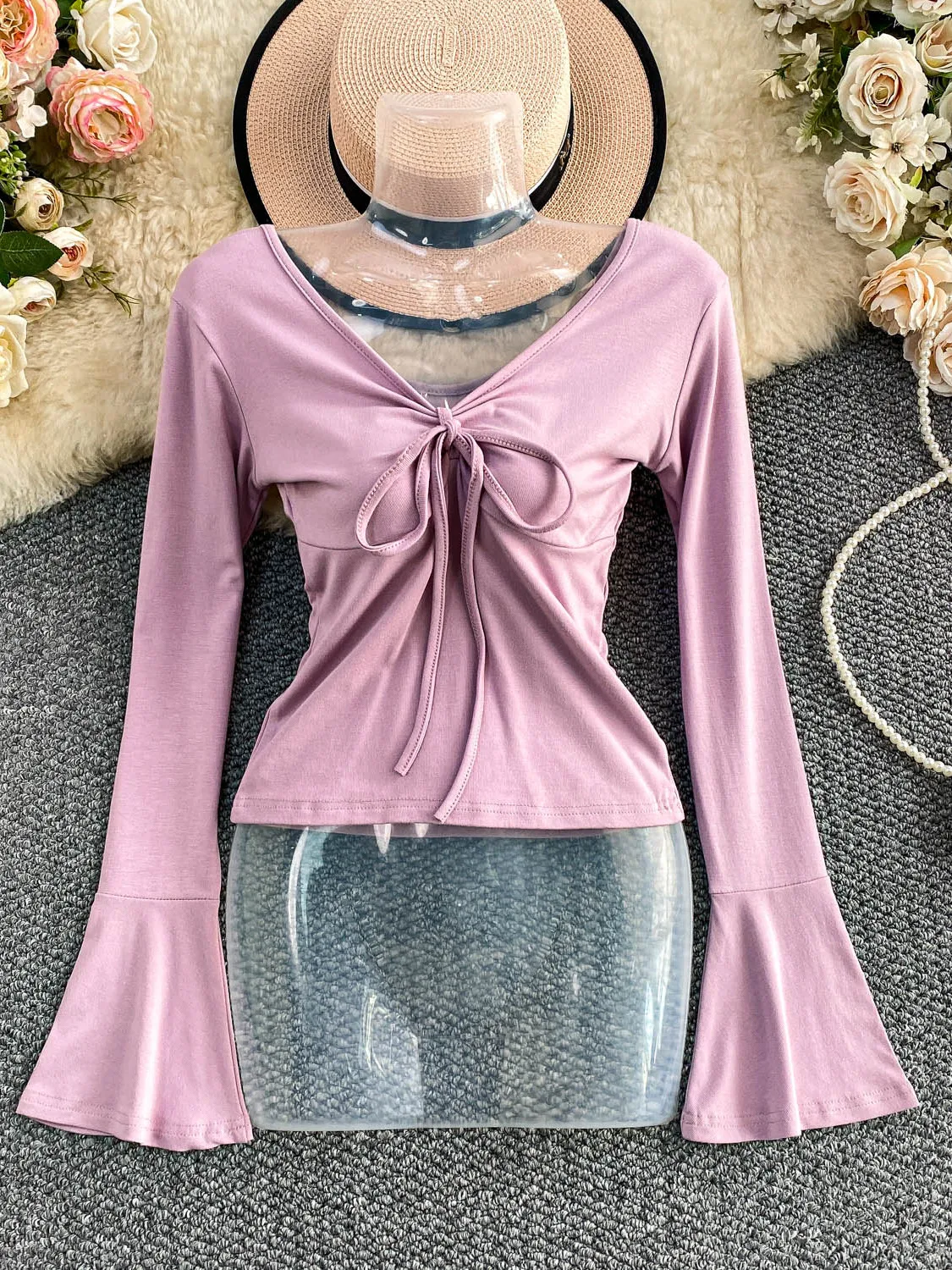 Seksowna, pikantna dziewczyna w dzianinowym, długim swetrze z dekoltem w serek, paskiem, wyszczuplającym krojem i dzwonkowymi rękawami, casualowy styl na jesień, moda damska.