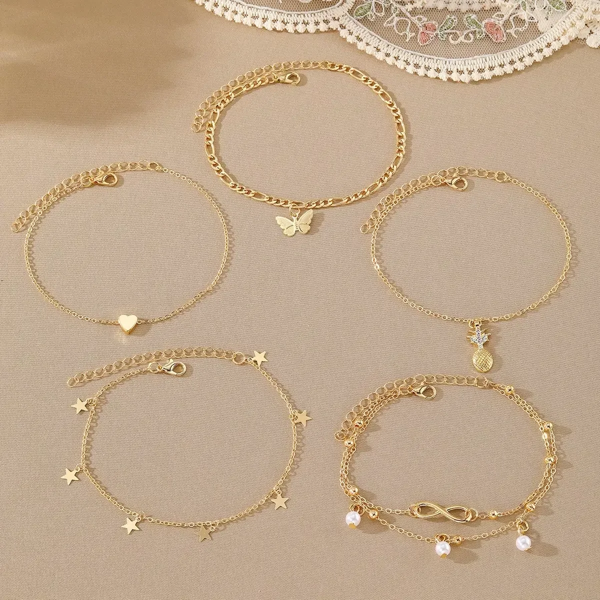Juego de 5 pulseras de tobillo estilo bohemio con dijes de piña, perla, mariposa, corazón, estrella e infinito, en tono dorado, para mujer.
