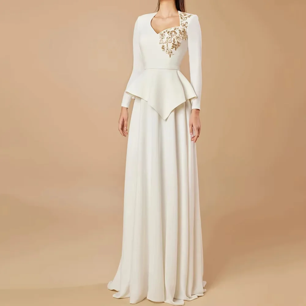 V‑neck long‑sleeve white evening gown with delicate chest embroidery, fitted waist and flowy floor‑length skirt. Modest style fo