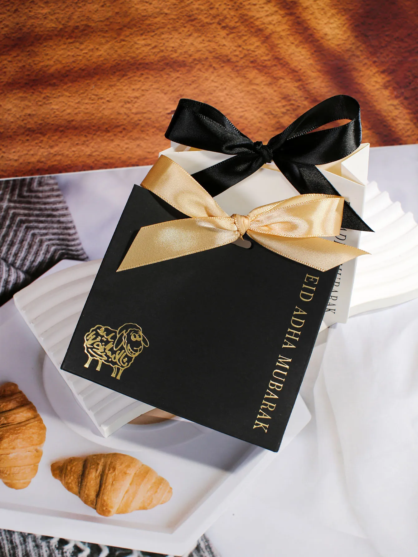 Exquisita caja de regalo para Eid al Adha, esquema de colores blanco y negro, elementos dorados llamativos, elegante decoración de cinta