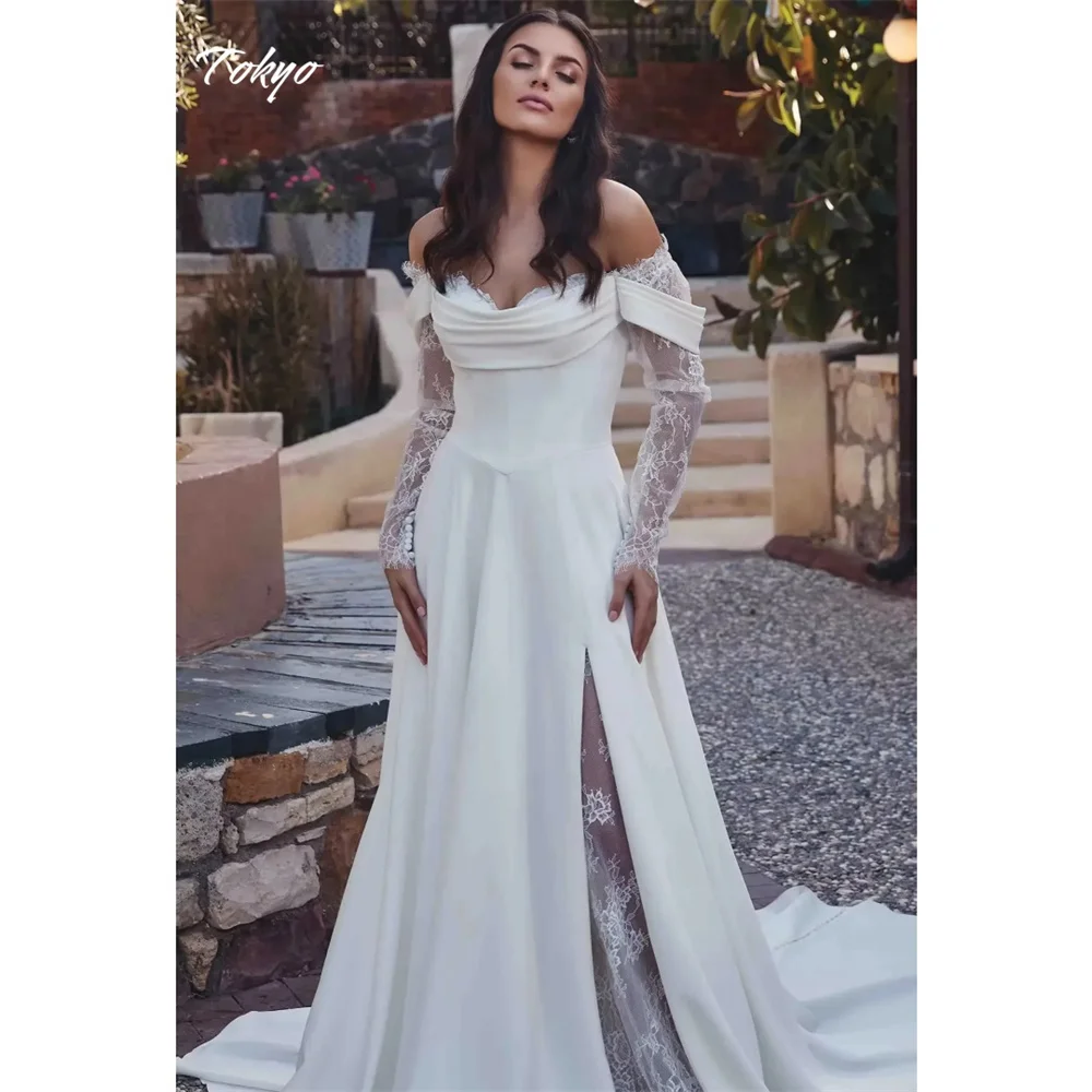 Suknia ślubna w stylu Tokyo, biała, z odkrytymi ramionami, z długim rękawem, o kroju litery A, z trenem dworskim, z wysokim rozcięciem z boku.