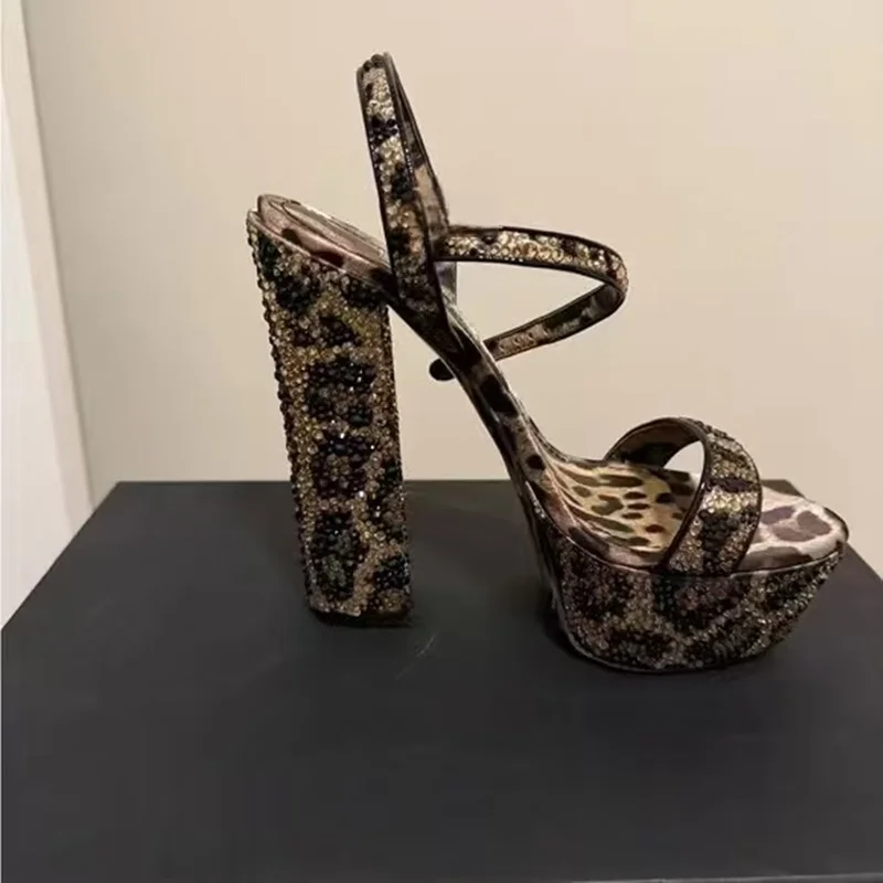 Seksowne platformy na masywnym obcasie typu chunky z paskiem wokół kostki, zapinane na klamrę, z odkrytymi palcami, w wyrazistym wzorze panterki, eleganckie na wieczorne wyjścia.