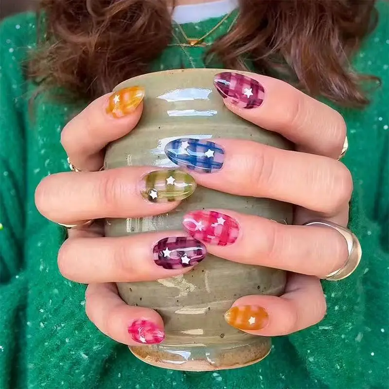 24 faux ongles courts en forme d'amande, transparents et colorés, à paillettes en forme d'étoile, avec un design à carreaux dégradé brillant.