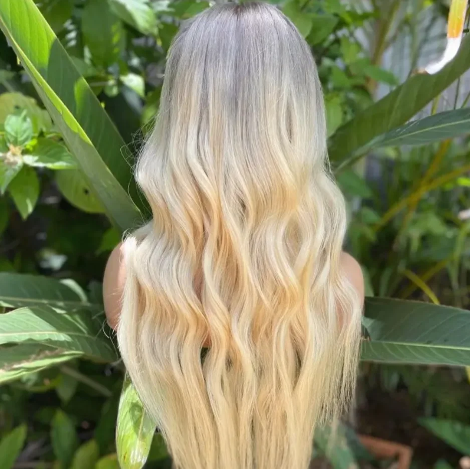 Peruka syntetyczna typu lace front z ciemnymi odrostami, jasnoblondowa peruka, peruka z falą body wave, naturalna peruka falowana, wstępnie wyskubana linia włosów, blond peruka z miękką koronką.