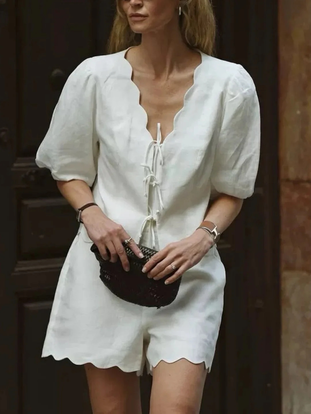 

Белый комплект из двух предметов: рубашка с V-образным вырезом и поясом, а также вышитые шорты из хлопка и льна. Модный женский летний комплект 2026 года.