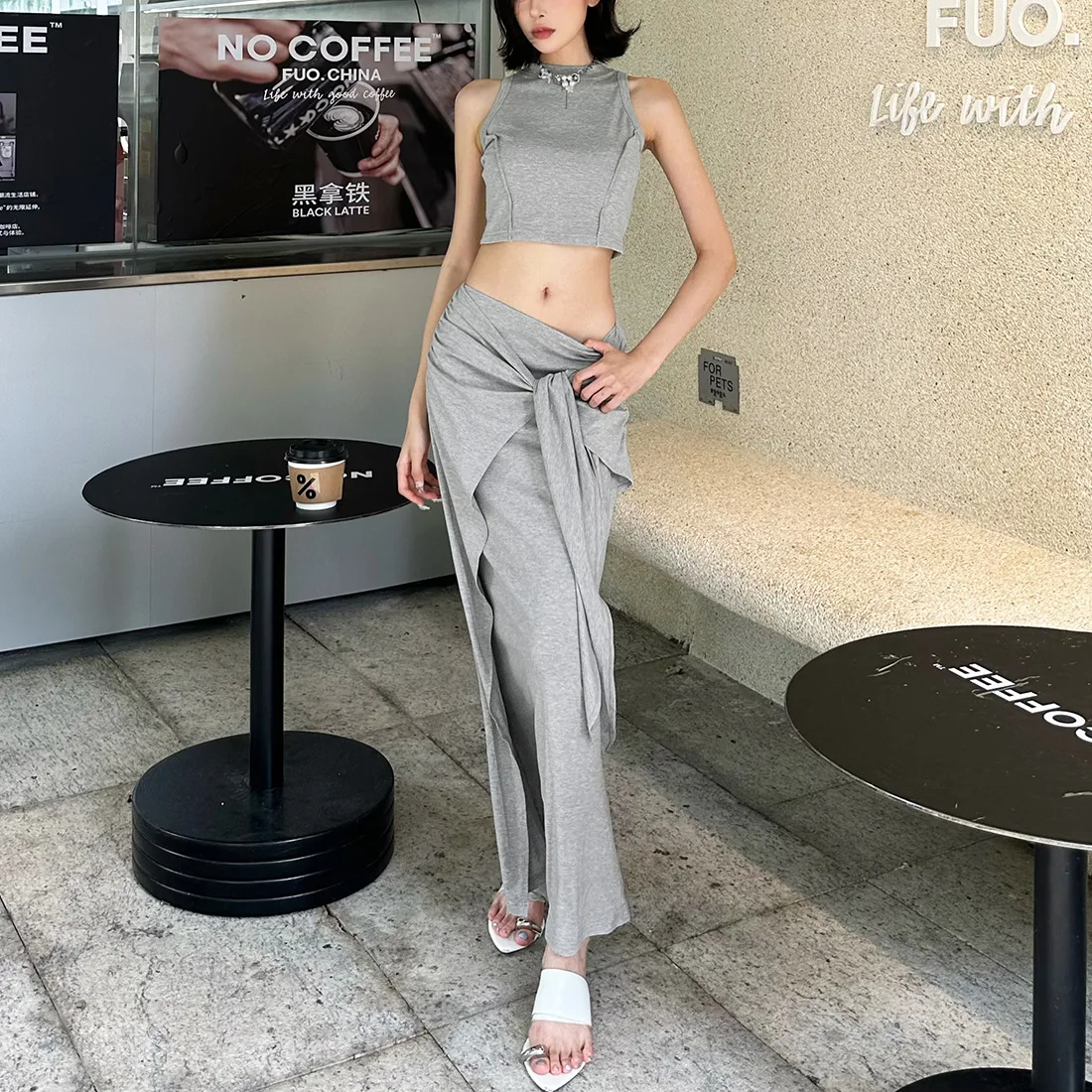 

Весна/Лето 2025: Элегантная и ношение — это топ без рукавов с узлом на талии и прямой длинной юбкой.