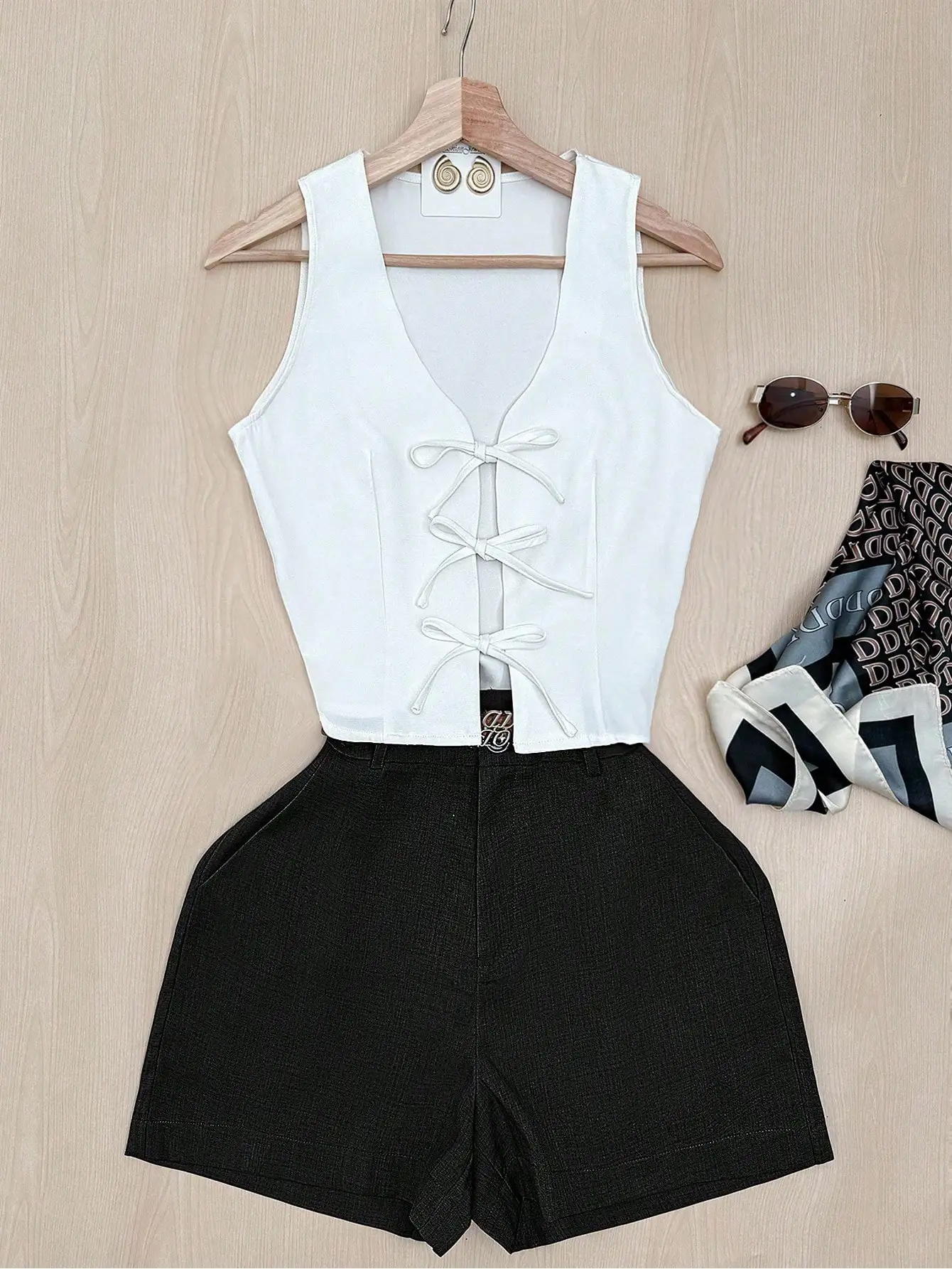 

Женский комплект: белый топ без рукавов с завязками спереди и черные шорты с высокой талией