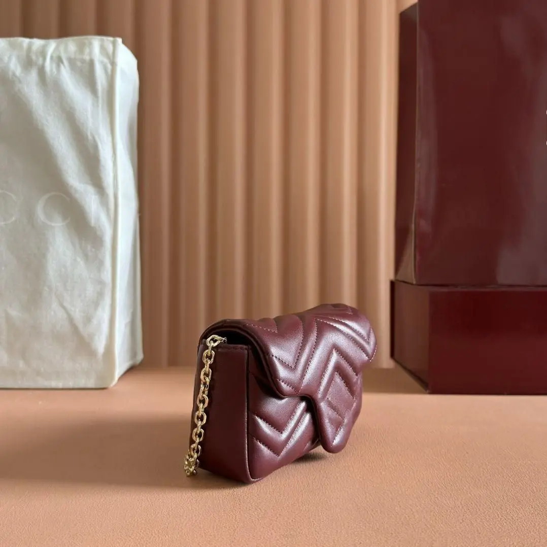 

Wine red quilted leather mini shoulder bag with V-stitch pattern and interwoven gold chain.