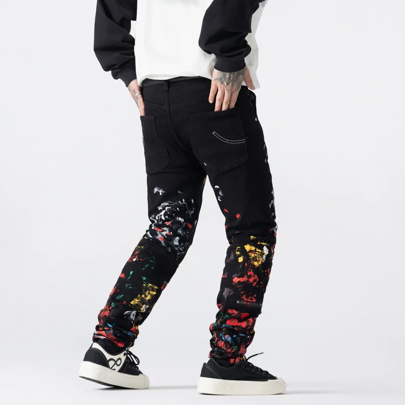 جينز أسود جديد لخريف 2025 مطبوع عليه جرافيتي بالحبر المرقط للرجال موضة الشارع سراويل راقية عصرية