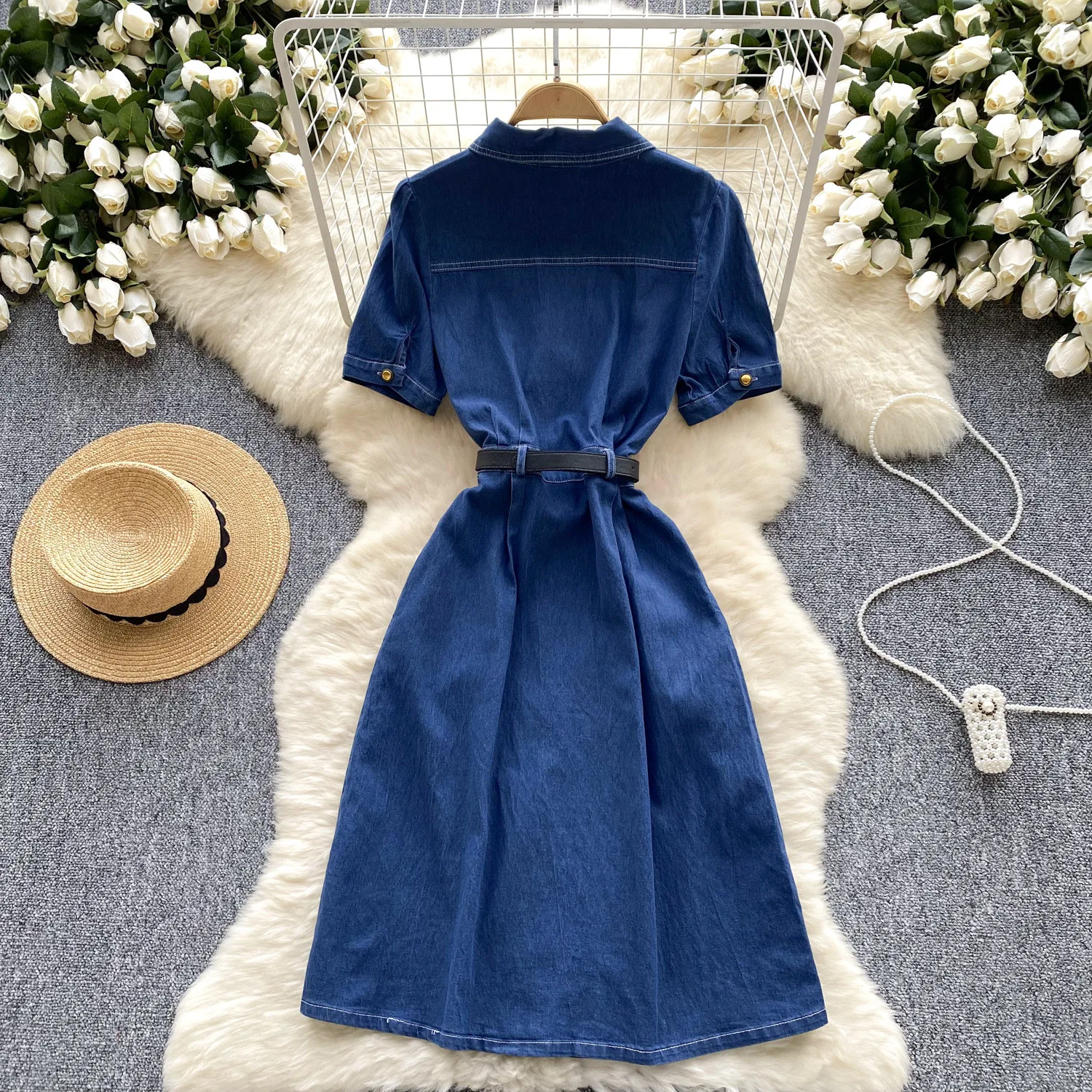 Un nuovo abito in denim alla moda estiva. Abito in denim a vita stretta con cintura monopetto in metallo a maniche corte con collo alto retrò per le donne