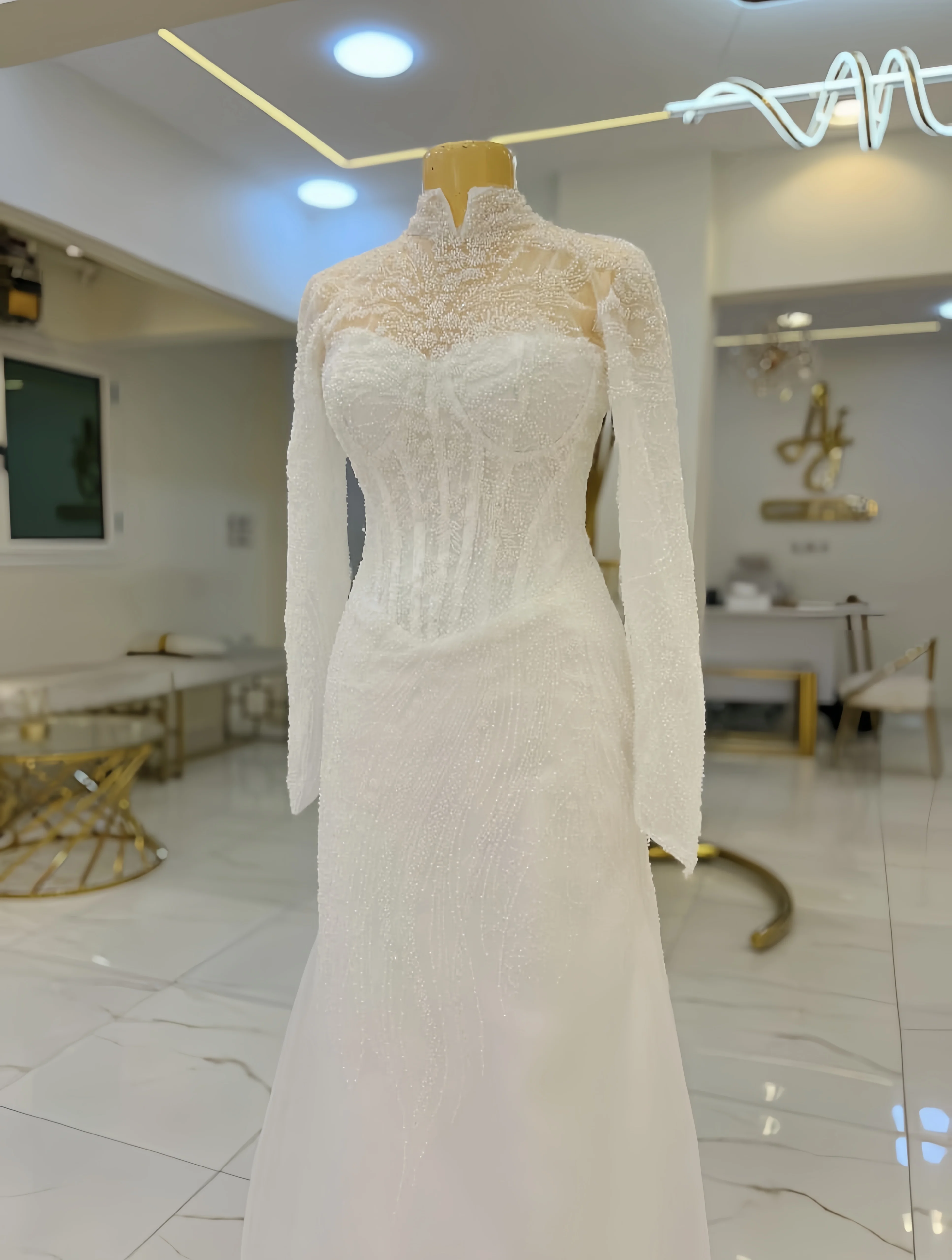 맞춤 제작된 고급스럽고 길고 반짝이는 하이넥 웨딩드레스와 긴 소매와 꼬리가 달린 웨딩드레스가 기차 앞바로 퍼지다