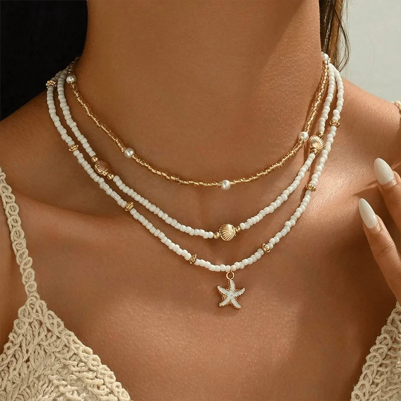 

Set of 3 Women's Fashion Chokers: A minimalist, girly-style layered necklace set featuring seed beads, faux pearls, and gold-tone accents, complete with seashell and starfish pendants—perfect for summer beach vacations.
