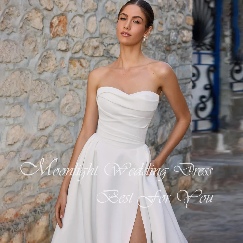 Klasyczna suknia ślubna w kształcie litery A z plisami, dekoltem w serduszko, wysokim rozcięciem z boku, odkrytymi ramionami, odkrytymi plecami, trenem zamiatającym i możliwością personalizacji.