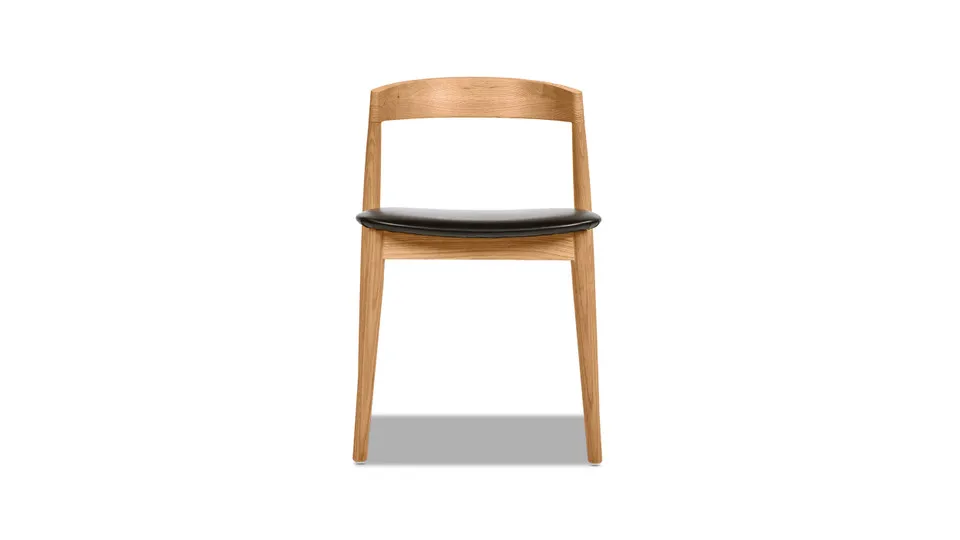 

Stacked carved oak dining chairs, warm natural brown oak and black synthetic leather