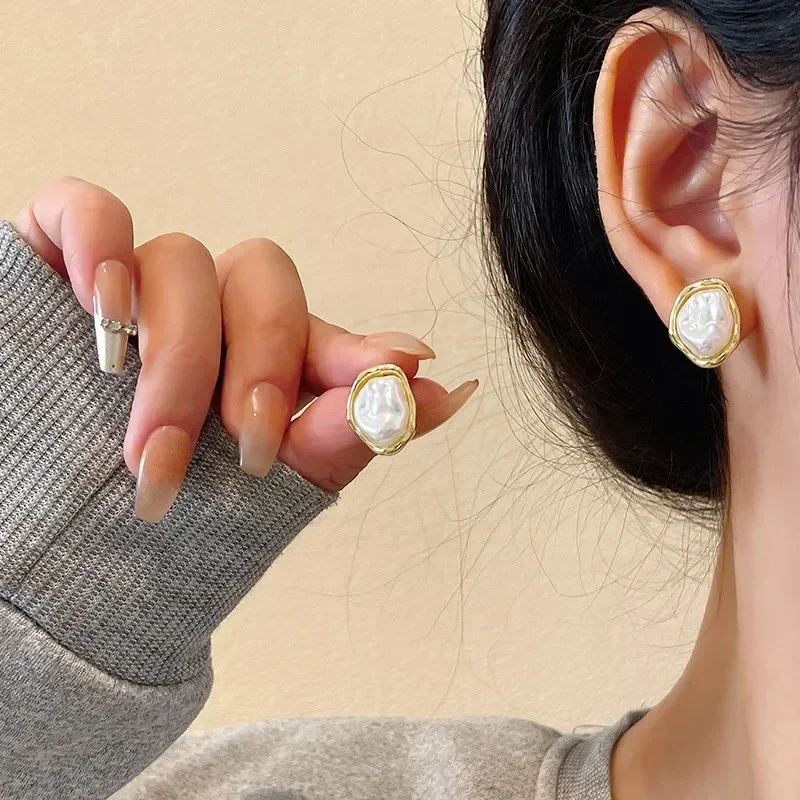 

Geometric Irregular Baroque Pearl Stud Earrings for Women, featuring a lustrous, organic-shaped faux pearl set in a polished gold-toned frame with a minimalist boho style.