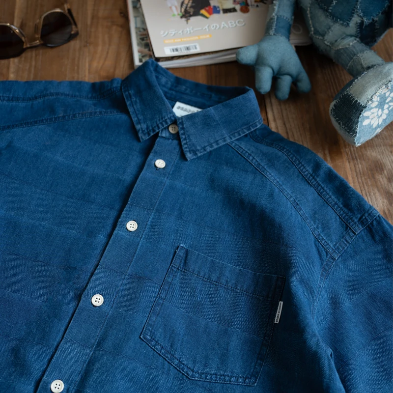 Indigo washed and woven loose French tooling style multi-pocket short-sleeved shirt
