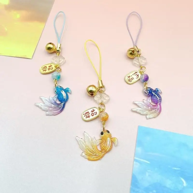 Buntes Handyband mit Farbverlauf und Goldfisch-Motiv, inklusive kleiner Glöckchen-Anhänger, ein schönes Geschenk für Taschen und Rucksäcke. – Detail 4