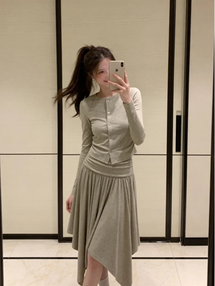 

Зеленый комплект из двух предметов: топ с круглым вырезом и длинными рукавами, облегающий, и асимметричная юбка А-силуэта с высокой талией. Весенний повседневный стиль.