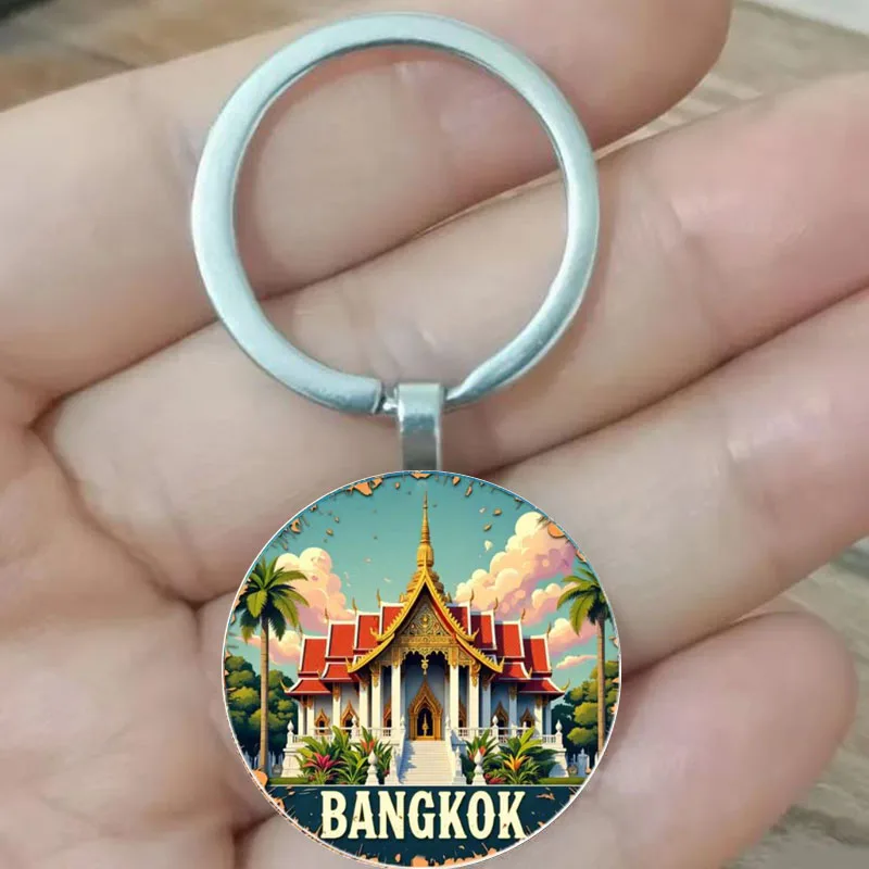 Un llavero circular con forma de templo de Bangkok rodeado por palmeras y nubes vibrantes. Muy adecuado para regalos navideños