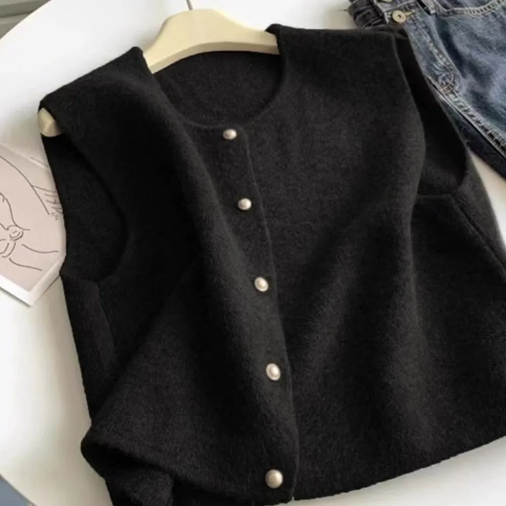 A gentle cashmere knitted vest with small golden buttons can be layered over a wool sleeveless vest top for autumn and winter