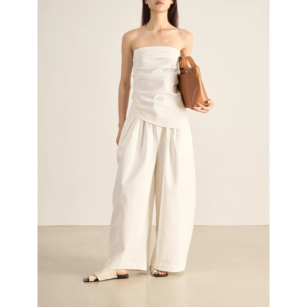 

Комплект: топ-бюстье с плиссировкой и асимметричным подолом, брюки-бананы с высокой талией и широкими штанинами. Женский модный летний наряд.