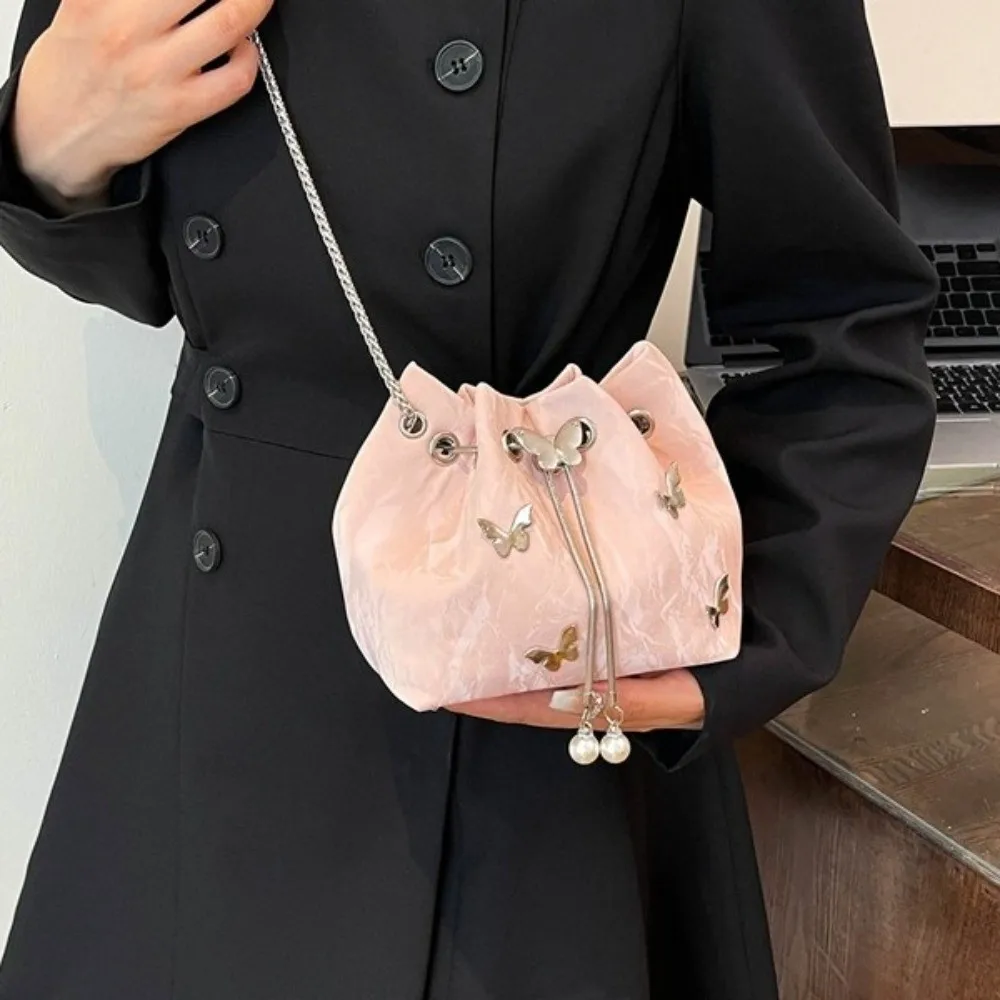 

PU Drawstring Bucket Bag Pearl Pendant Metal Butterfly Accent Chain Crossbody Bag Adjustable Strap Minimalist Design