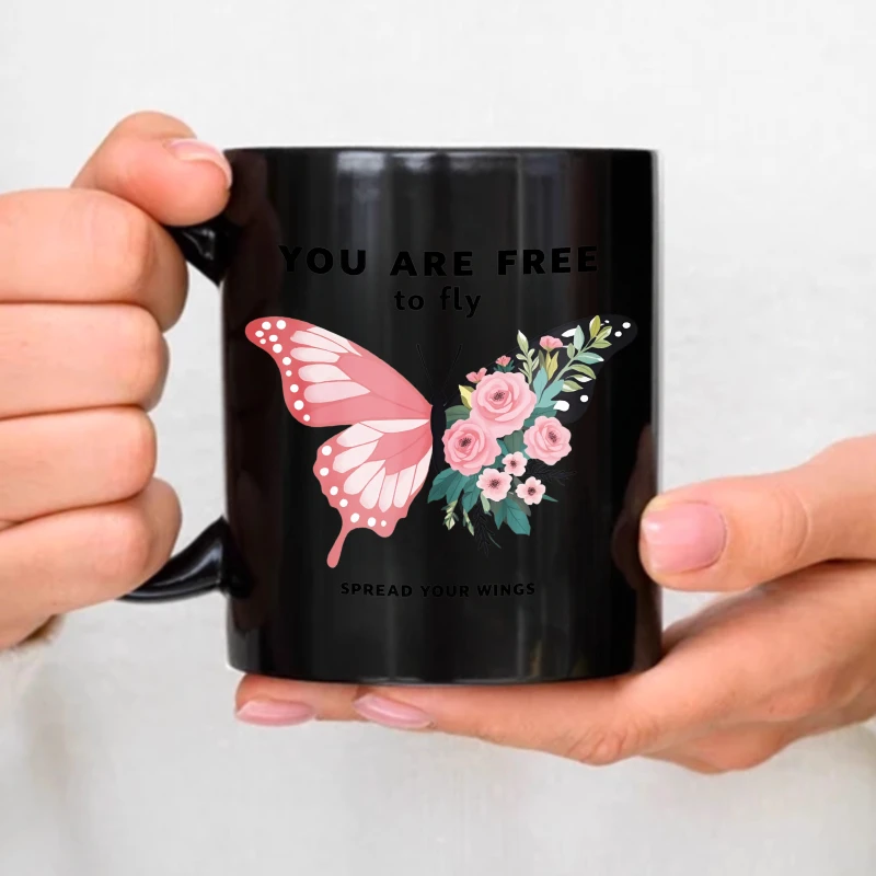 A black ceramic mug with a pink butterfly and floral design and an inspirational quote to 
