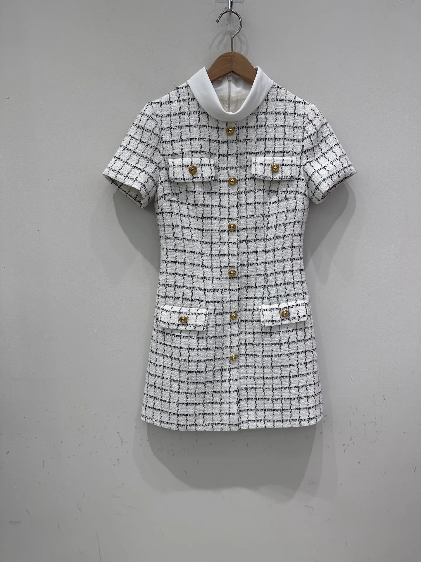 Een afslankende en nauwsluitende jurk met enkele rij knopen, een vleugje elegantie en een korte rok voor de herfst van 2025