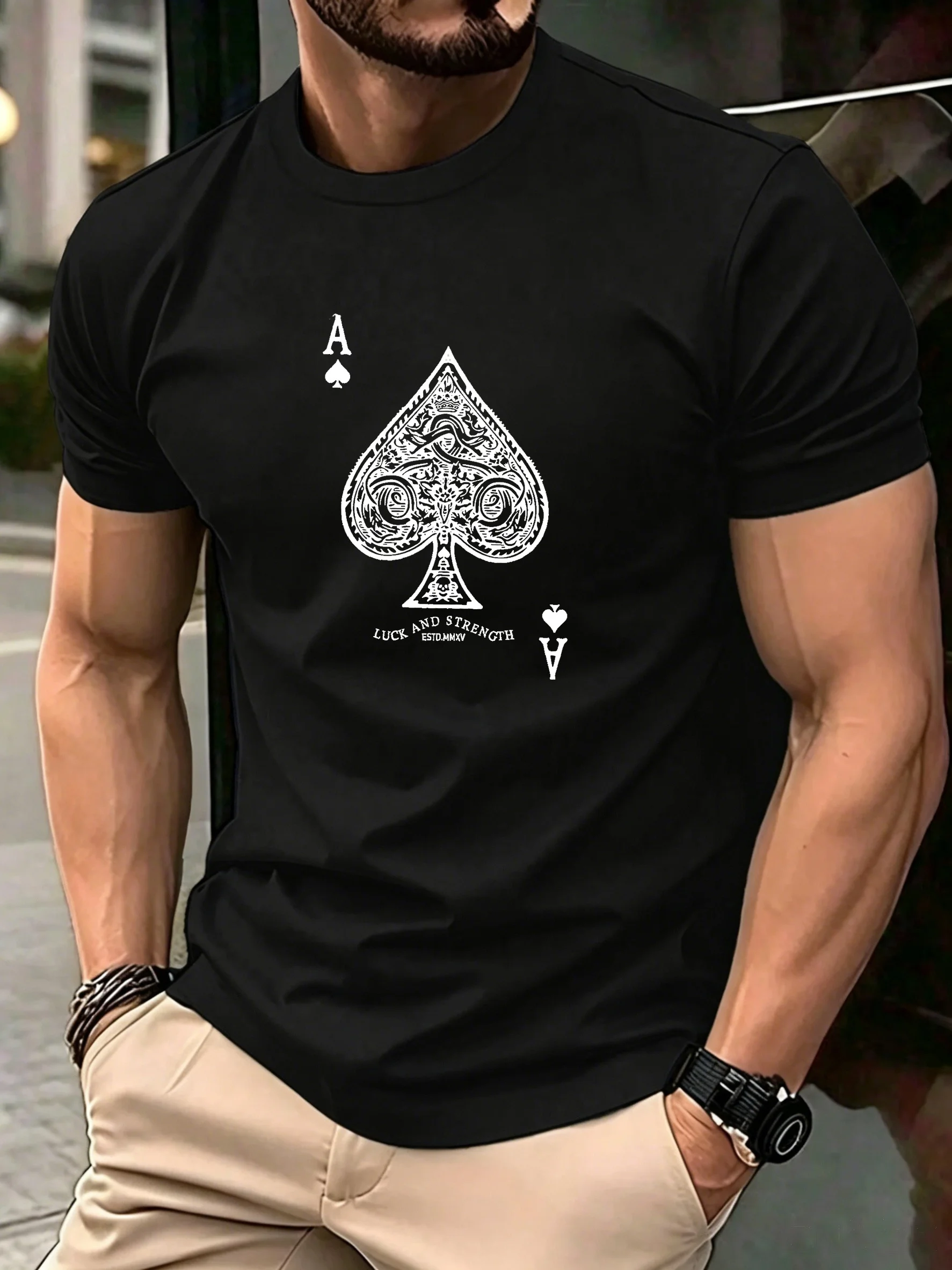 Camiseta de manga corta para hombre disponible en negro y blanco, con un delicado diseño grabado de una pica negra de cartas, una letra simétrica y un texto inspirador impreso. Corte holgado, estilo urbano de verano, top informal con cuello redondo