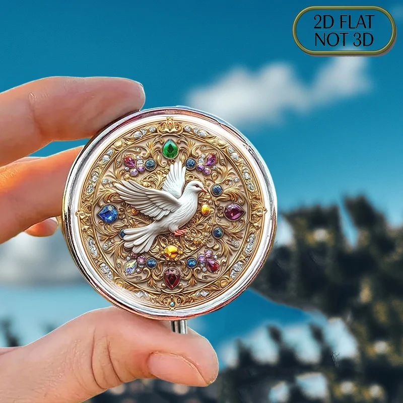 A flat, portable, round metal pill box, adorned with a mandala design featuring a white dove surrounded by jewels, is perfect for storing daily medications and supplements, ideal for organizing vitamins, small accessories, or coins, and makes a great gift for a loved one