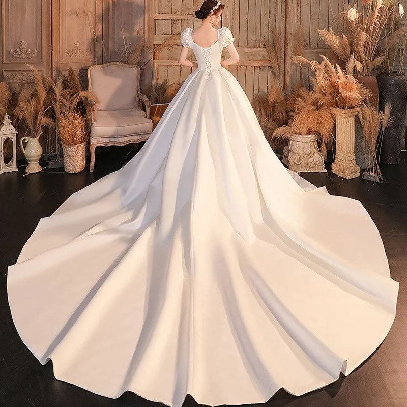 肩が一つになったサテン生地のドレスで、腕を覆う大きなトレーンが付いています。