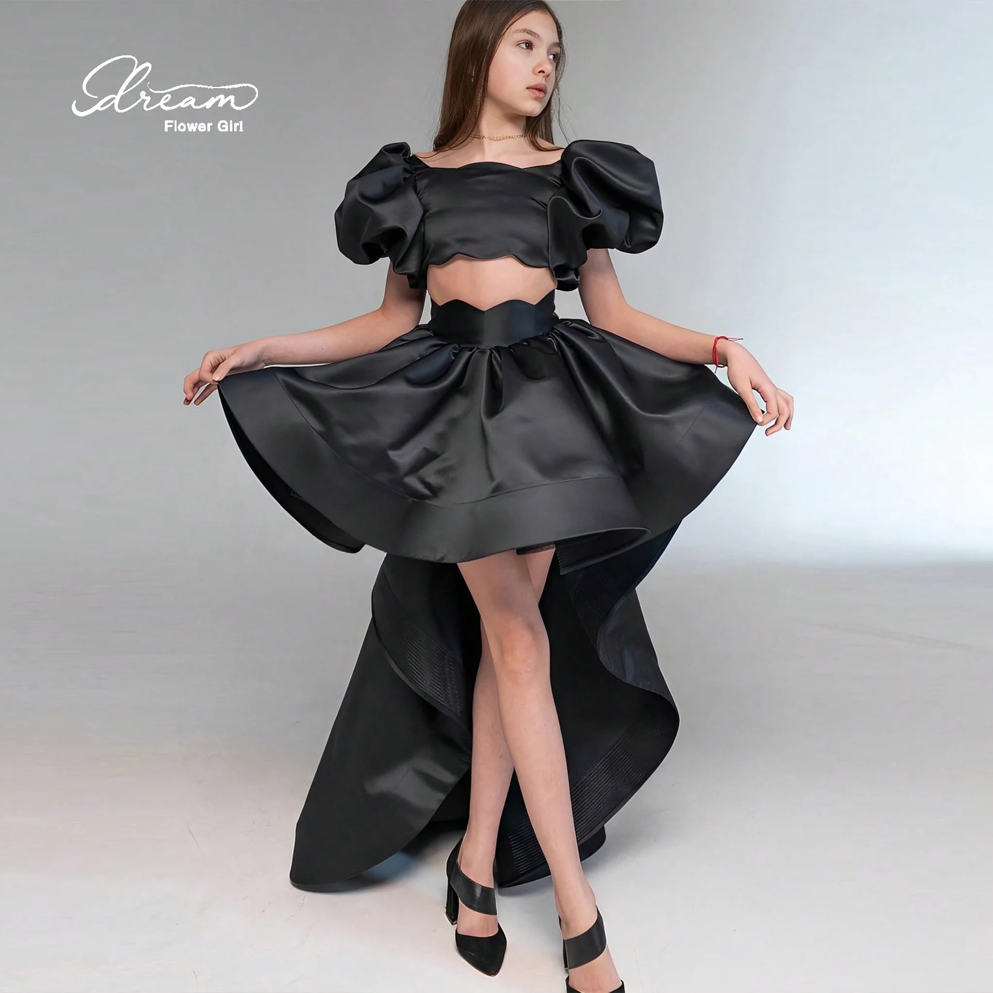 Girls' formal ball gown featuring a black flat collar cape sleeves a voluminous skirt a cut-out waist and an asymmetrical he