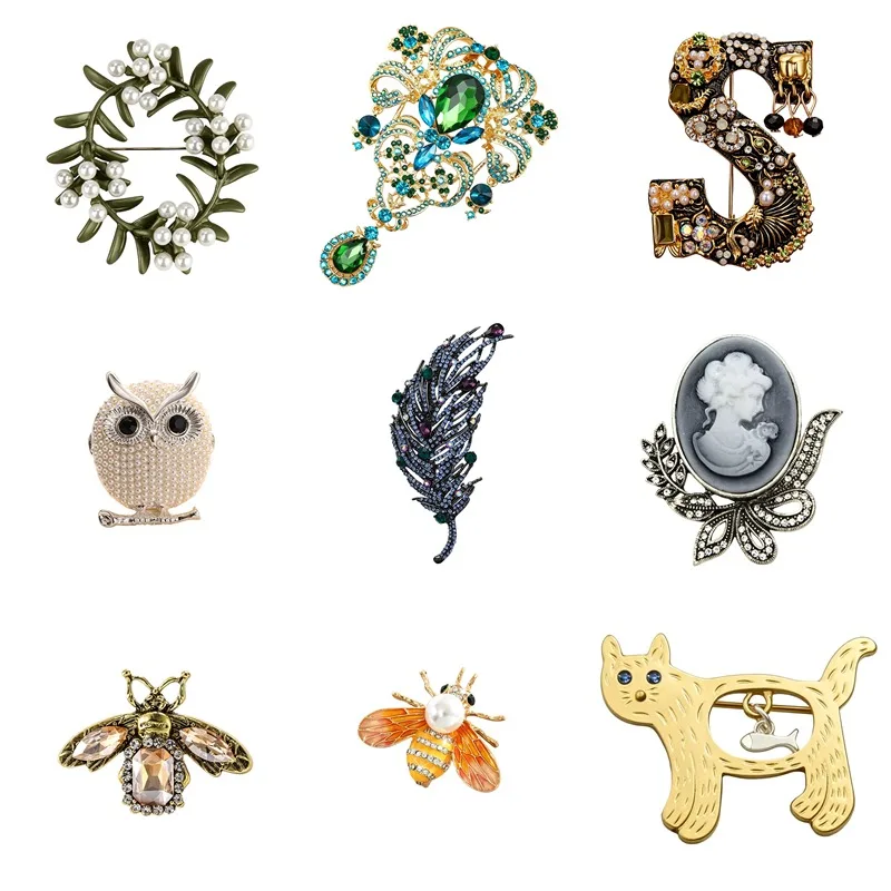 Various brooches: wreath, pearl owl, crystal feather, relief portrait, champagne bee, orange enamel bee, cat pendant with fish