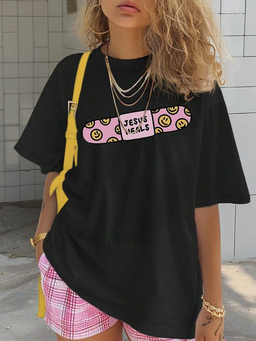 

Plus - Size Religious Graphic Tee, Black Short - Sleeve with “JESUS HEALS” Bandage Print