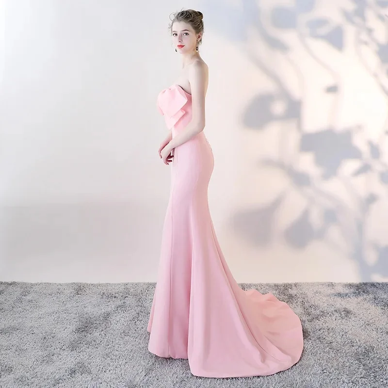 Soft pink strapless fitted floor-length gown decorated with sweet bow on chest. Strapless neckline shows delicate shoulders, sli