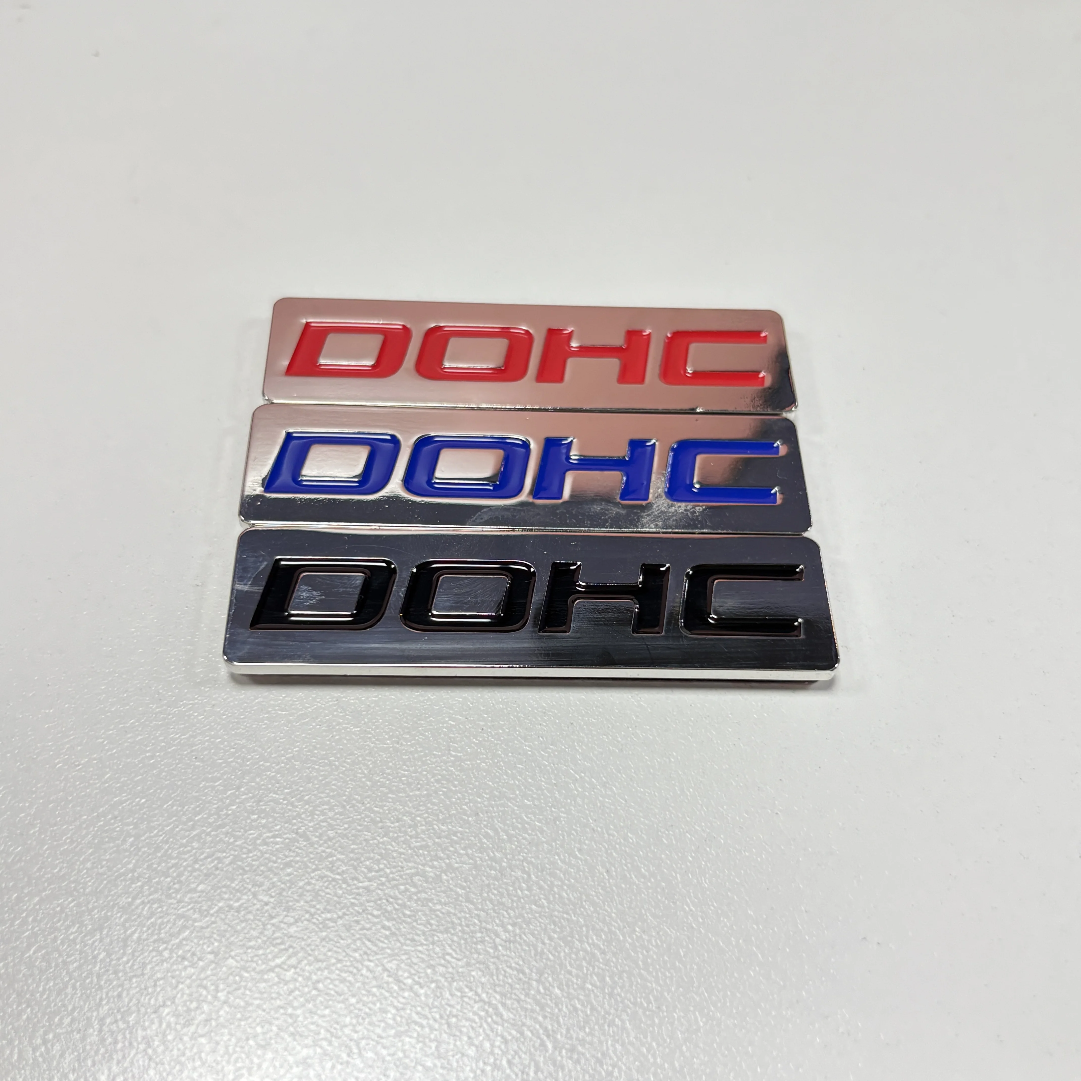 EMBLEMAT METALOWY DOHC MOTYR KORZYSTNYCH ZAWODÓW, NIEBIESKI / CZERWONY / CZARNY, NA BAGAŻNIK, MASKĘ, DRZWI, CHROMOWANY