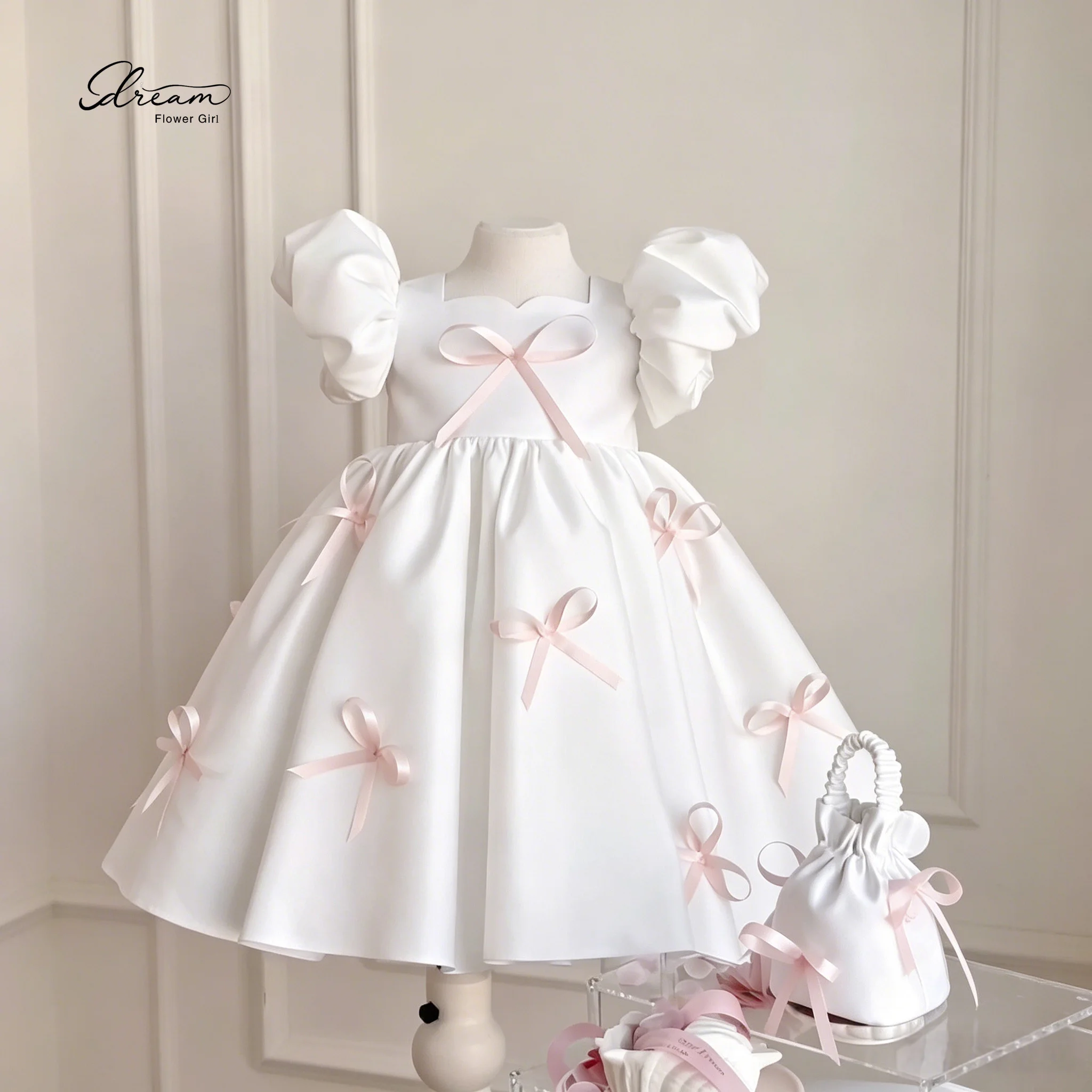 Exquisite Floor-Length White Formal Gown for Children Featuring Puff Sleeves a Voluminous Skirt and Pink Bow Accents