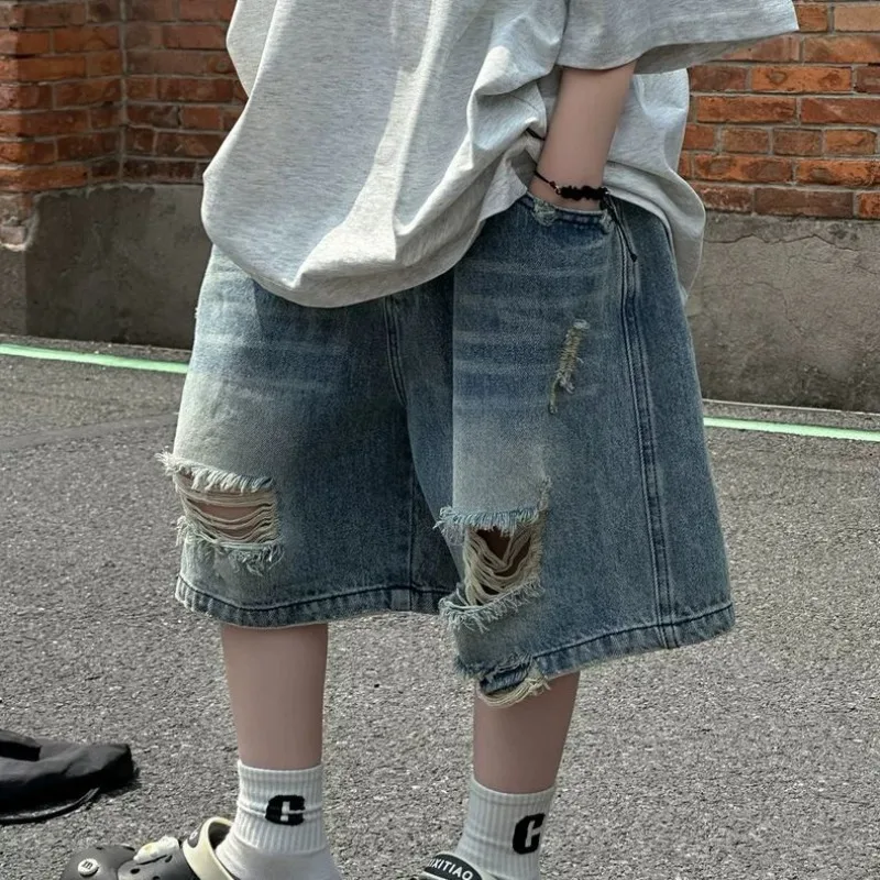 Bermuda Jeans Infantil Masculina Rasgada com Efeito Olho de Gato, Caimento Solto, Verão 2026 ​