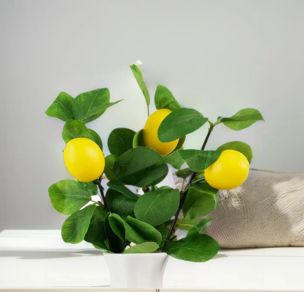 Echt aussehende gelbe Zitronenfrucht mit künstlichen Blättern. Künstliche Blumen für die Inneneinrichtung von Hotel-Wohnkultur. Künstliche Blumen