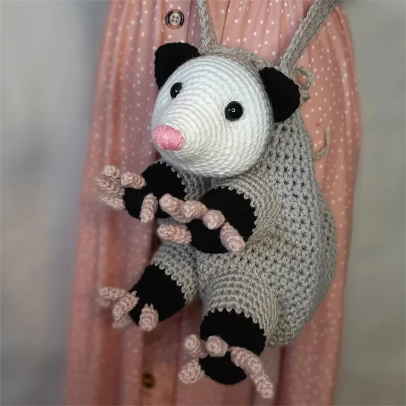 

Очаровательная сумка через плечо ручной работы из вязания крючком опоссума в форме с милым выражением лица и нежными деталями розовой лапы