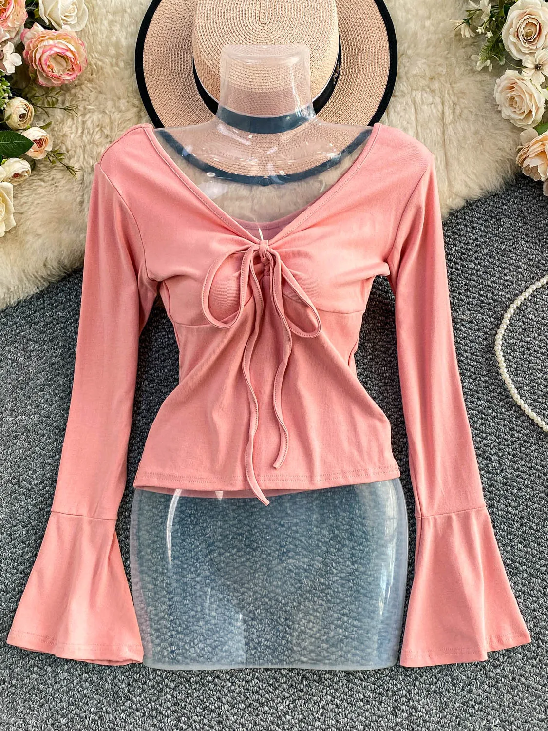 Seksowna, pikantna dziewczyna w dzianinowym, długim swetrze z dekoltem w serek, paskiem, wyszczuplającym krojem i dzwonkowymi rękawami, casualowy styl na jesień, moda damska.