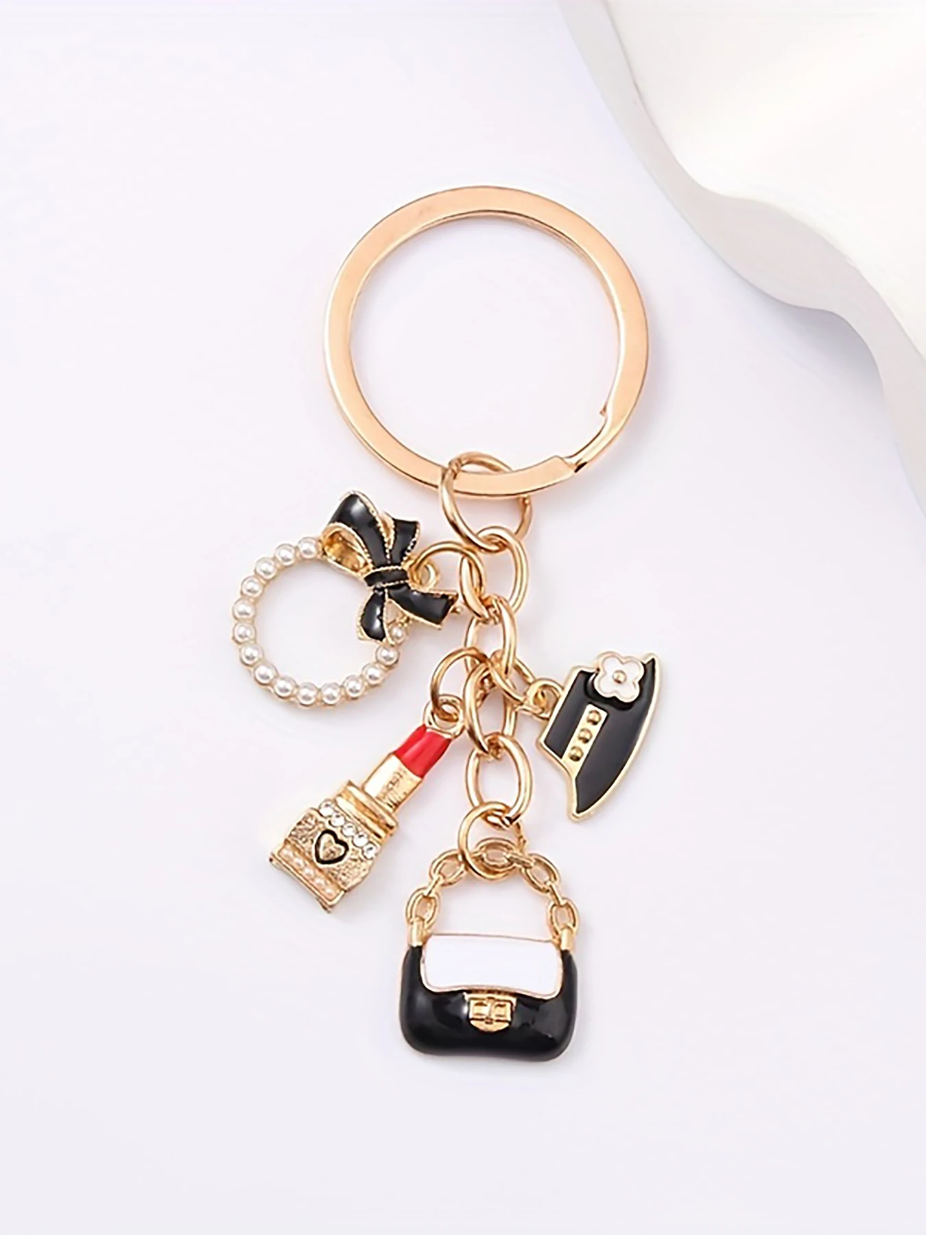 Stylish bag charm keychain with lipstick, hat, ring & dripping embellishments, trendy accessory for cars and bags.