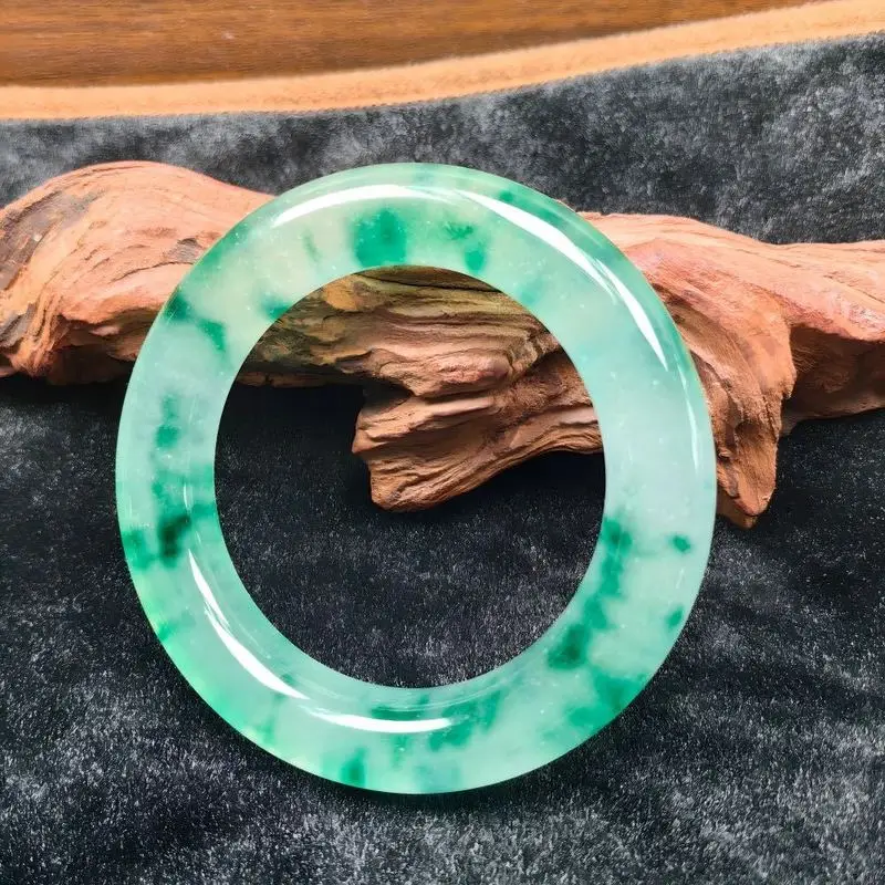 Un fondo blanco con una pulsera redonda de color verde vibrante que emana una calidad translúcida, luminosa y similar a la de la esmeralda, adornada con...