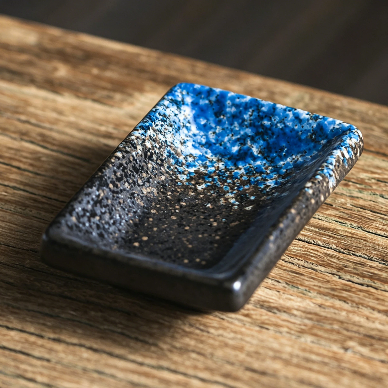 Rectangular ceramic dipping dish with raised edges and a blue and black mottled finish