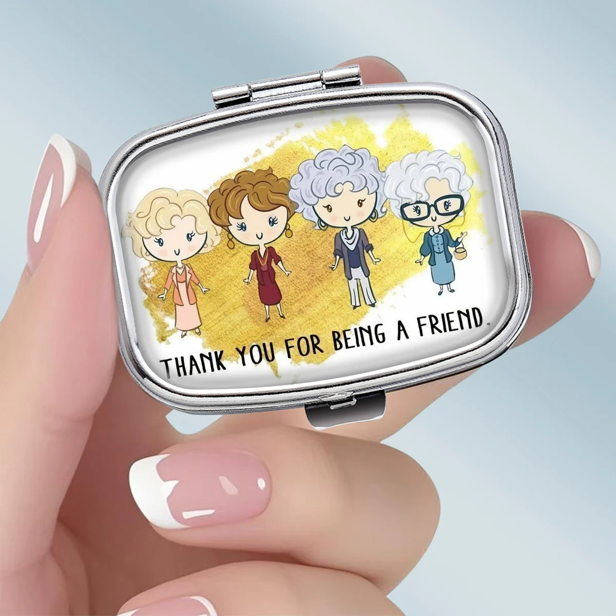 A portable square metal medicine box, featuring cartoon designs symbolizing companionship and friendship, designed with two compartments, perfect for elegantly storing your medication or supplements. It is very suitable for sorting and storing vitamins and small items.